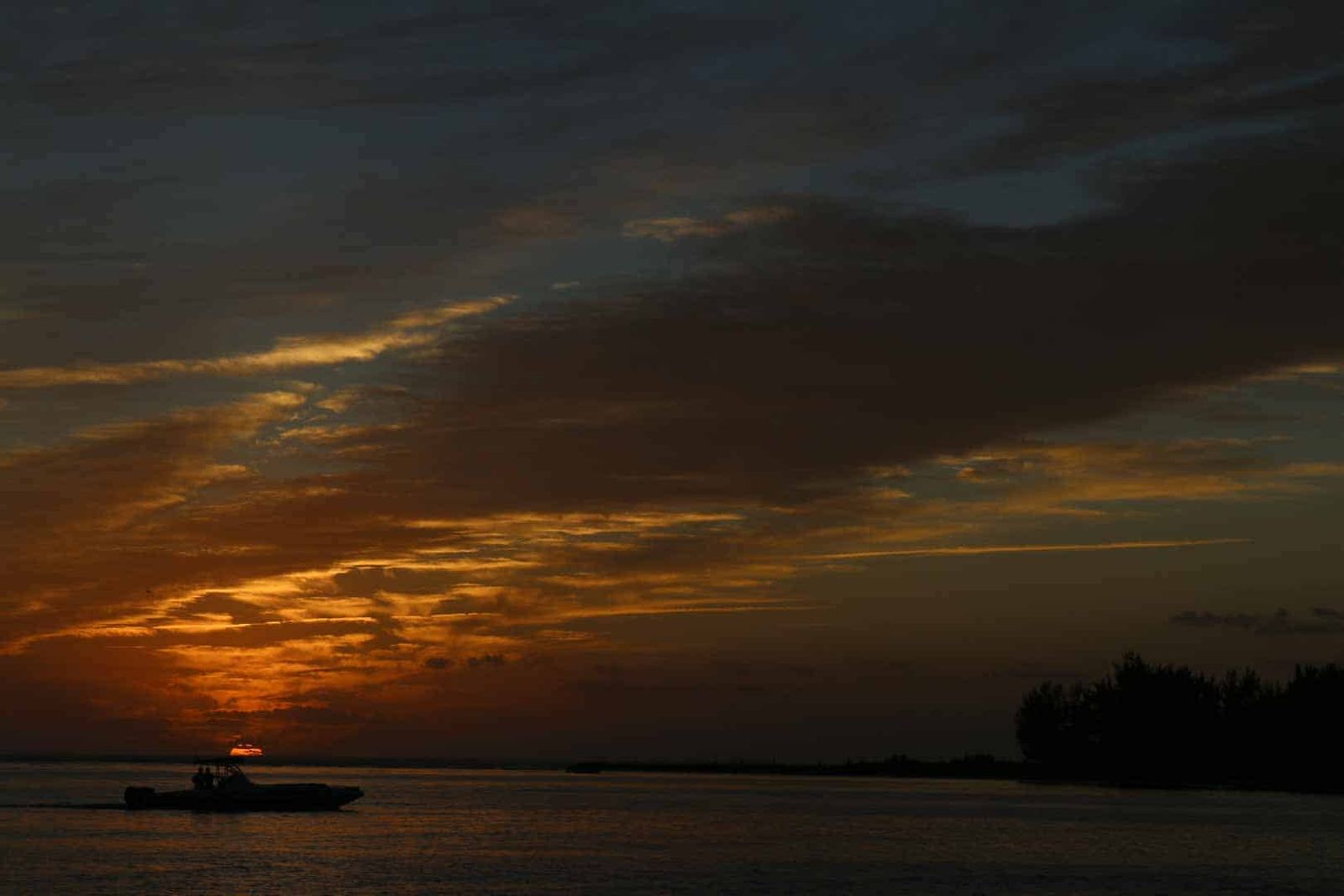 A center console running home in silhouette against a burning orange sunset sky