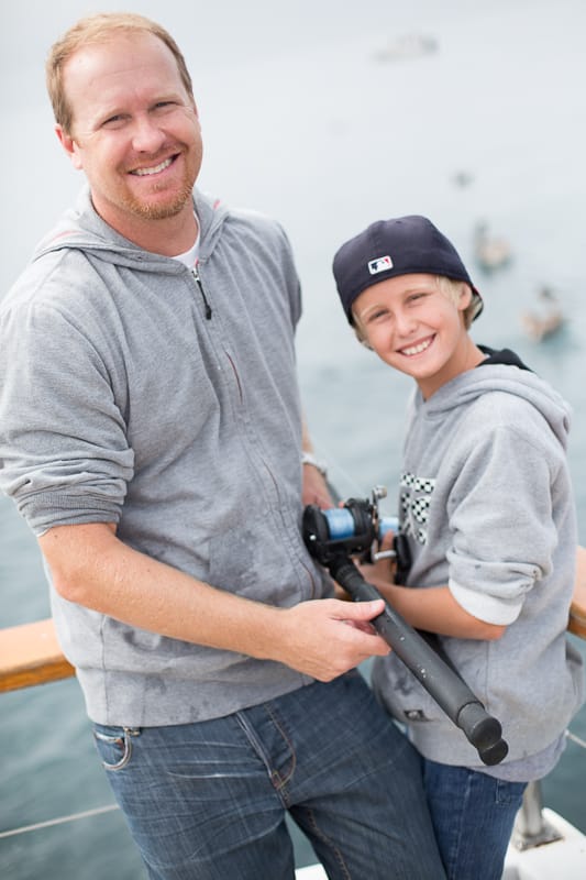 A man and a boy at the rail, conventional rod between them.