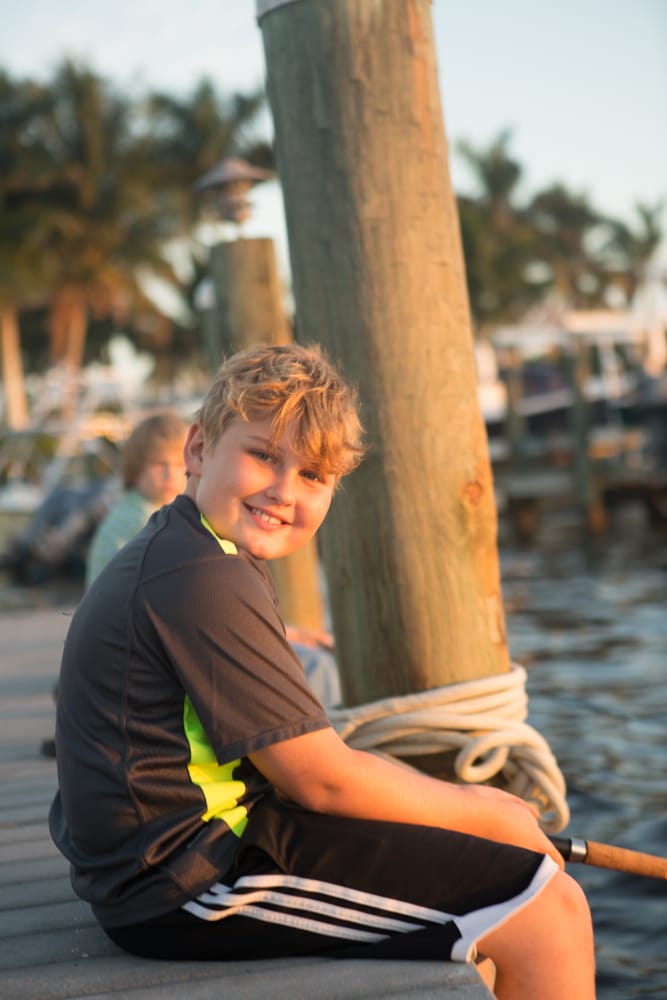 Sitting on the dock at golden hour, rod at his side.