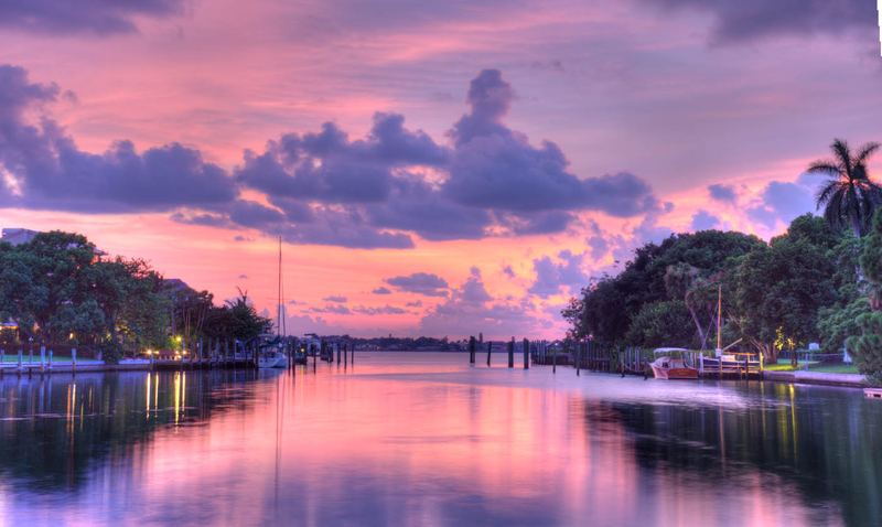 Pink and purple sunset reflecting off a calm Sarasota bayou lined with docked boats