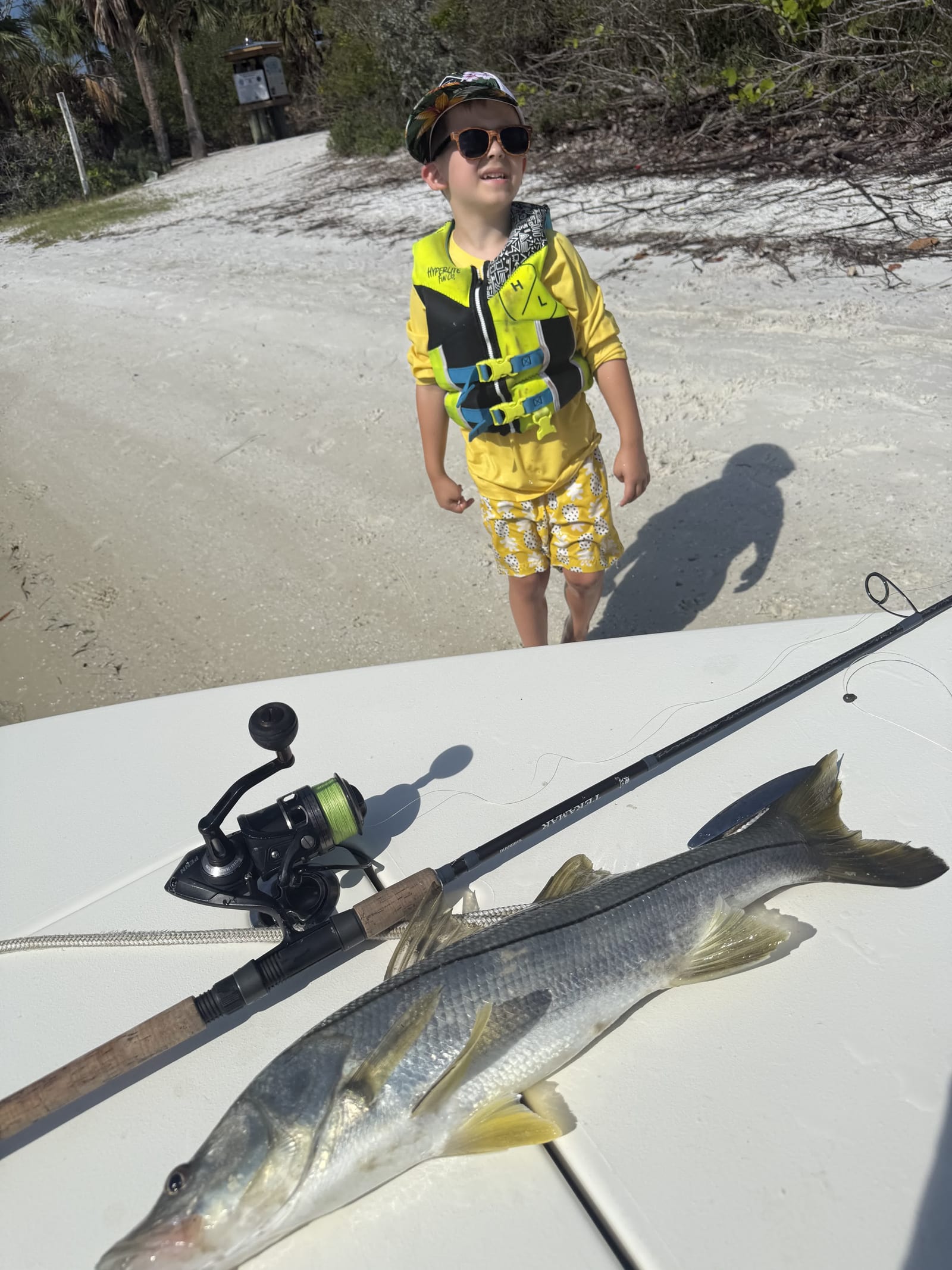 A young angler on the beach with a snook on the boat deck
