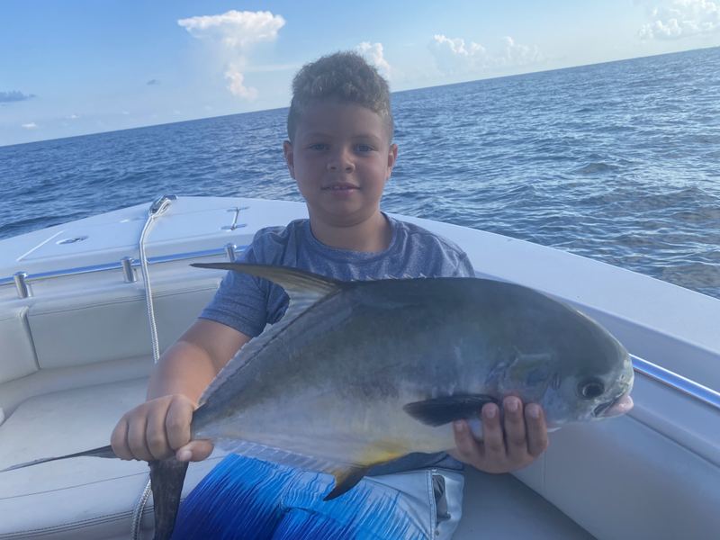 Kid holding a permit caught on a nearshore trip