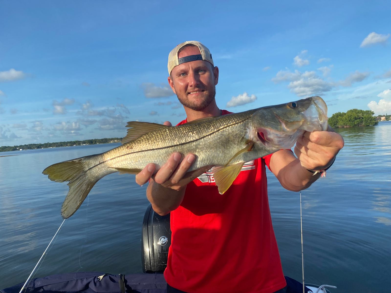 Angler holding a snook over the bay at dusk
