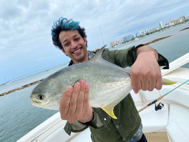 A Sarasota angler with a Florida pompano, the downtown skyline across the bay