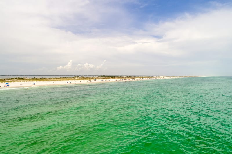 Green inshore water giving way to blue along a Gulf beach.
