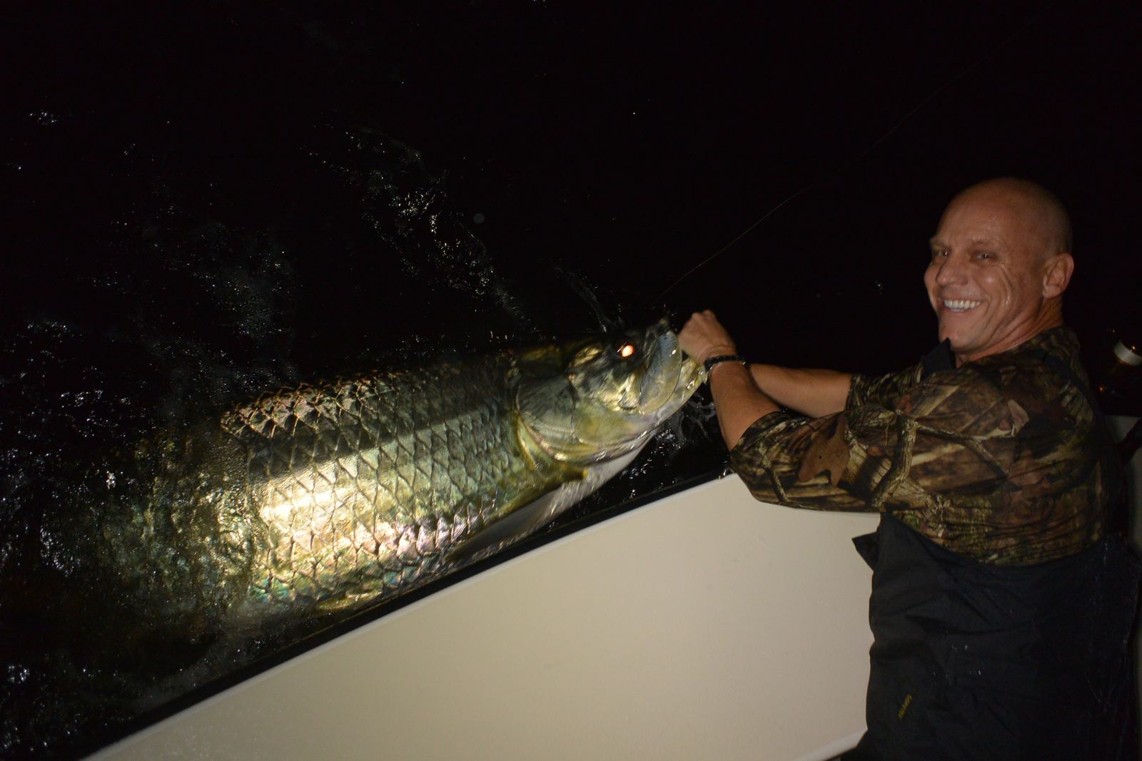 Capt. Steve boat-side with a big tarpon lit up in the dark on a night trip